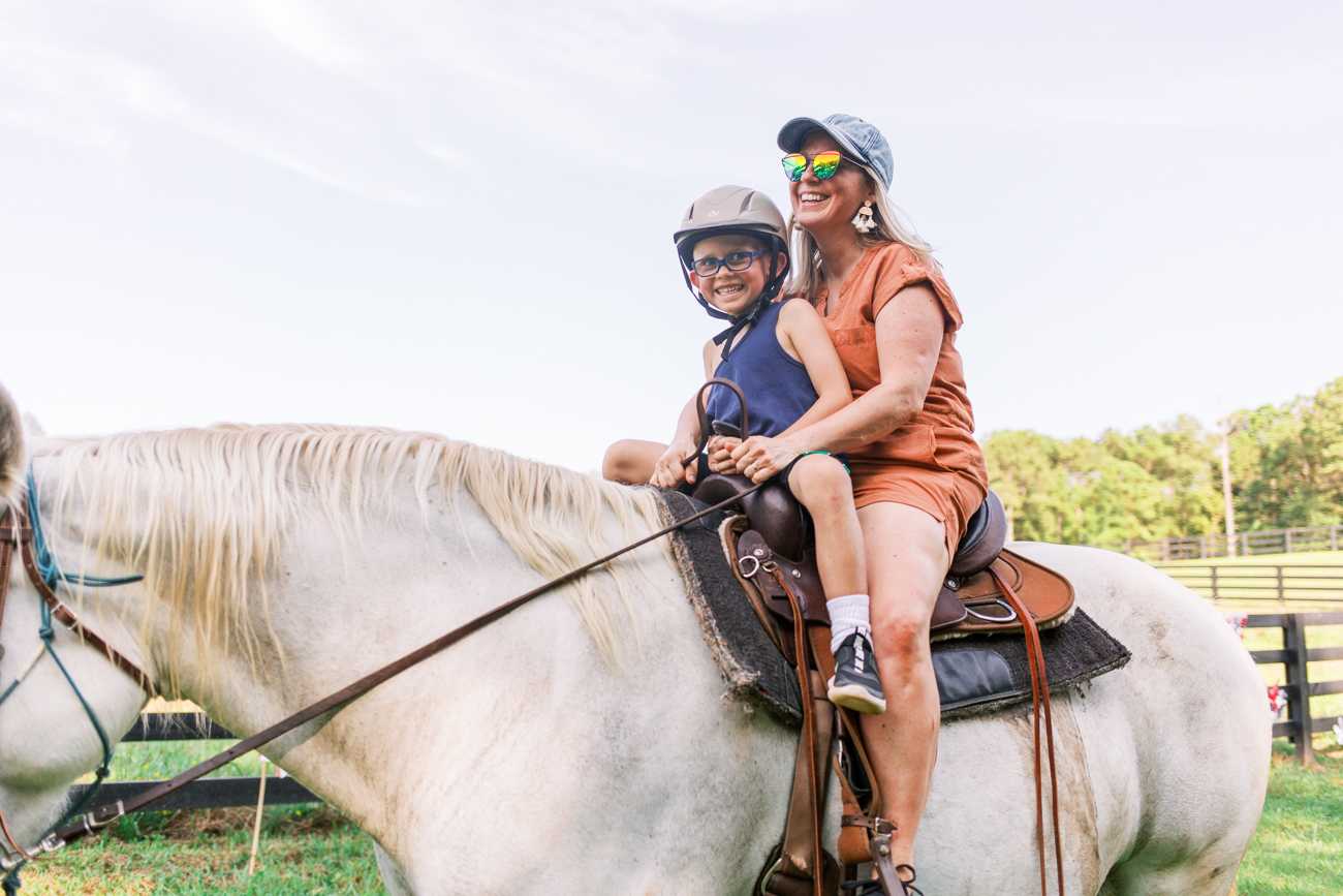 A mother and son horseback riding at Callidora Ranch near Atlanta on a white horse in tandem.